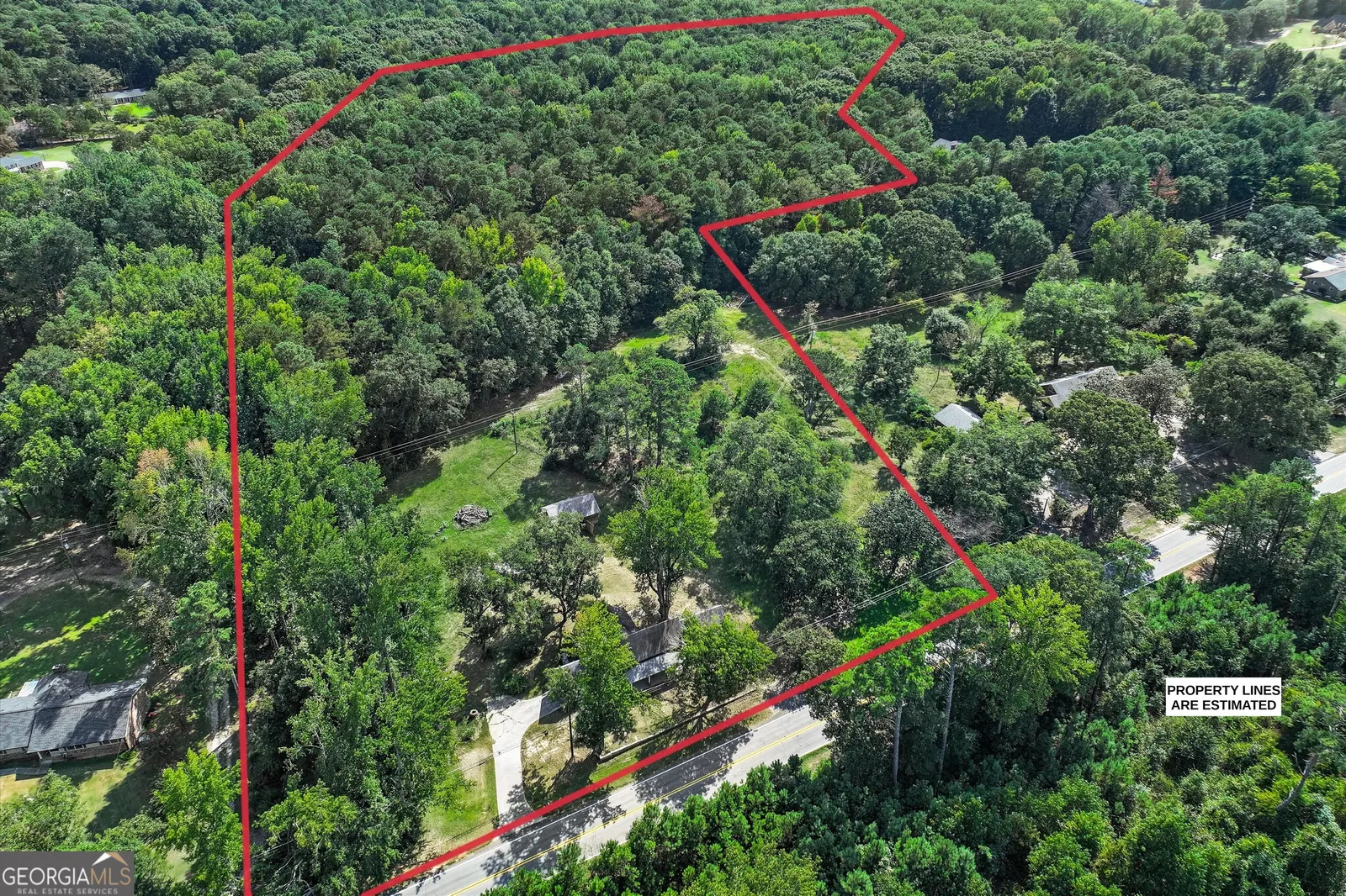 Aerial view with the 20.55-acre parcel boundary outlined in red across dense woodland