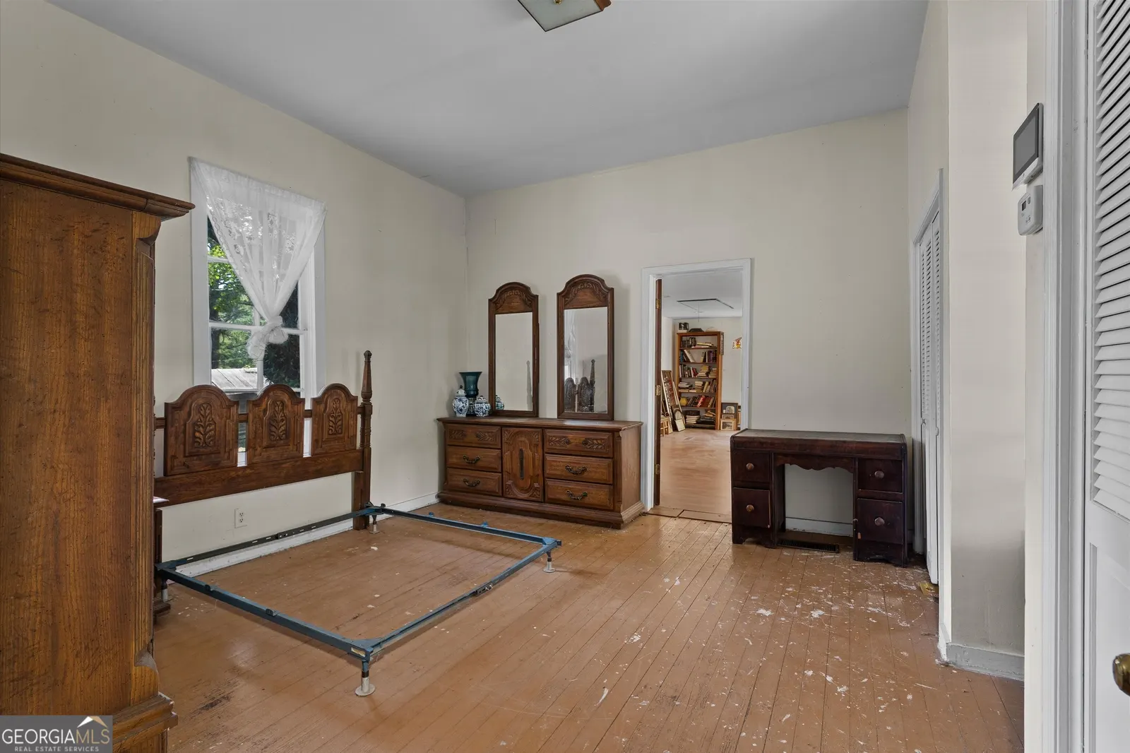 Bedroom with hardwood floor, an antique bed frame and a dresser with a mirror