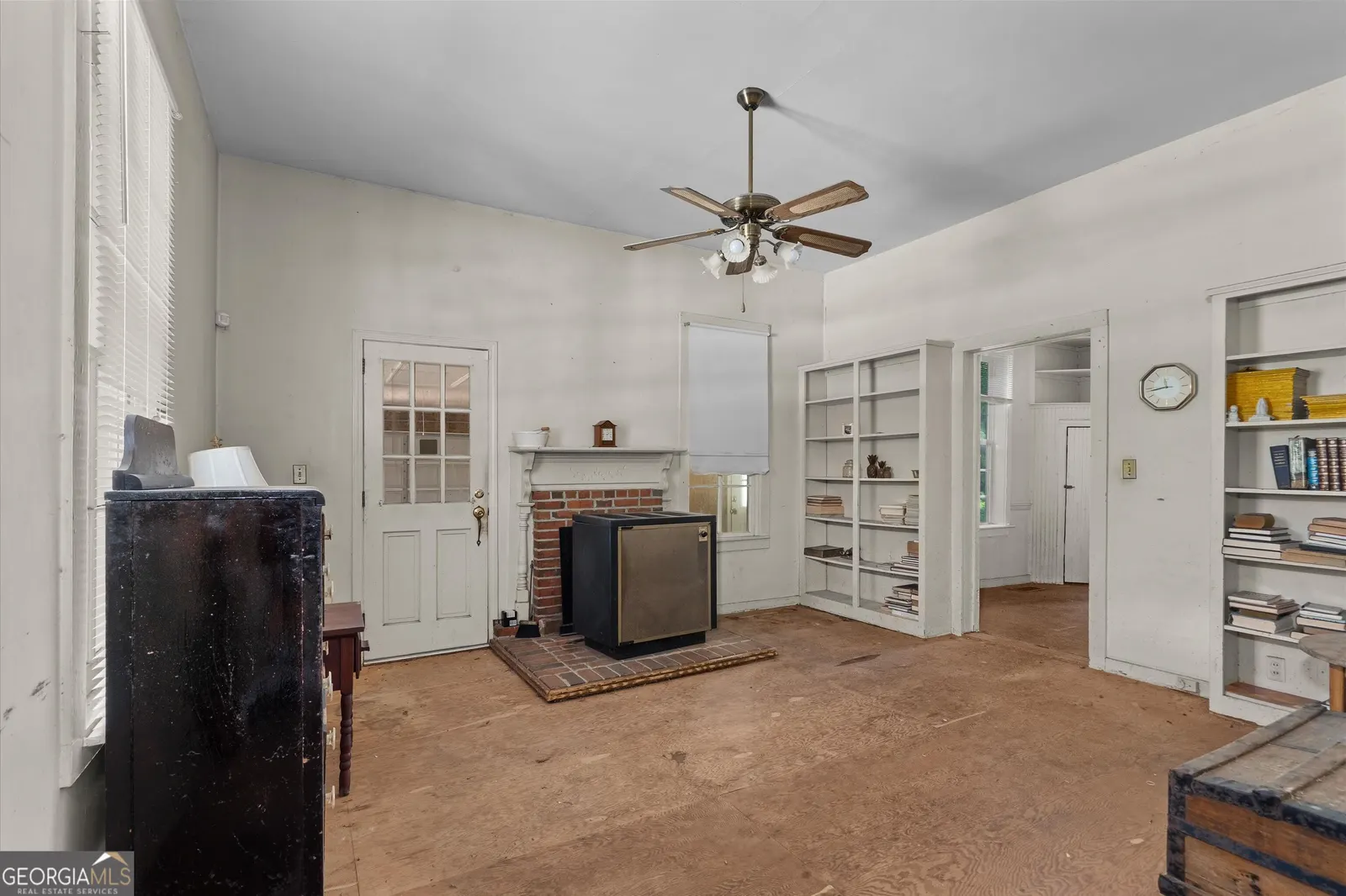 Living room with a brick fireplace, white built-in shelving and a ceiling fan