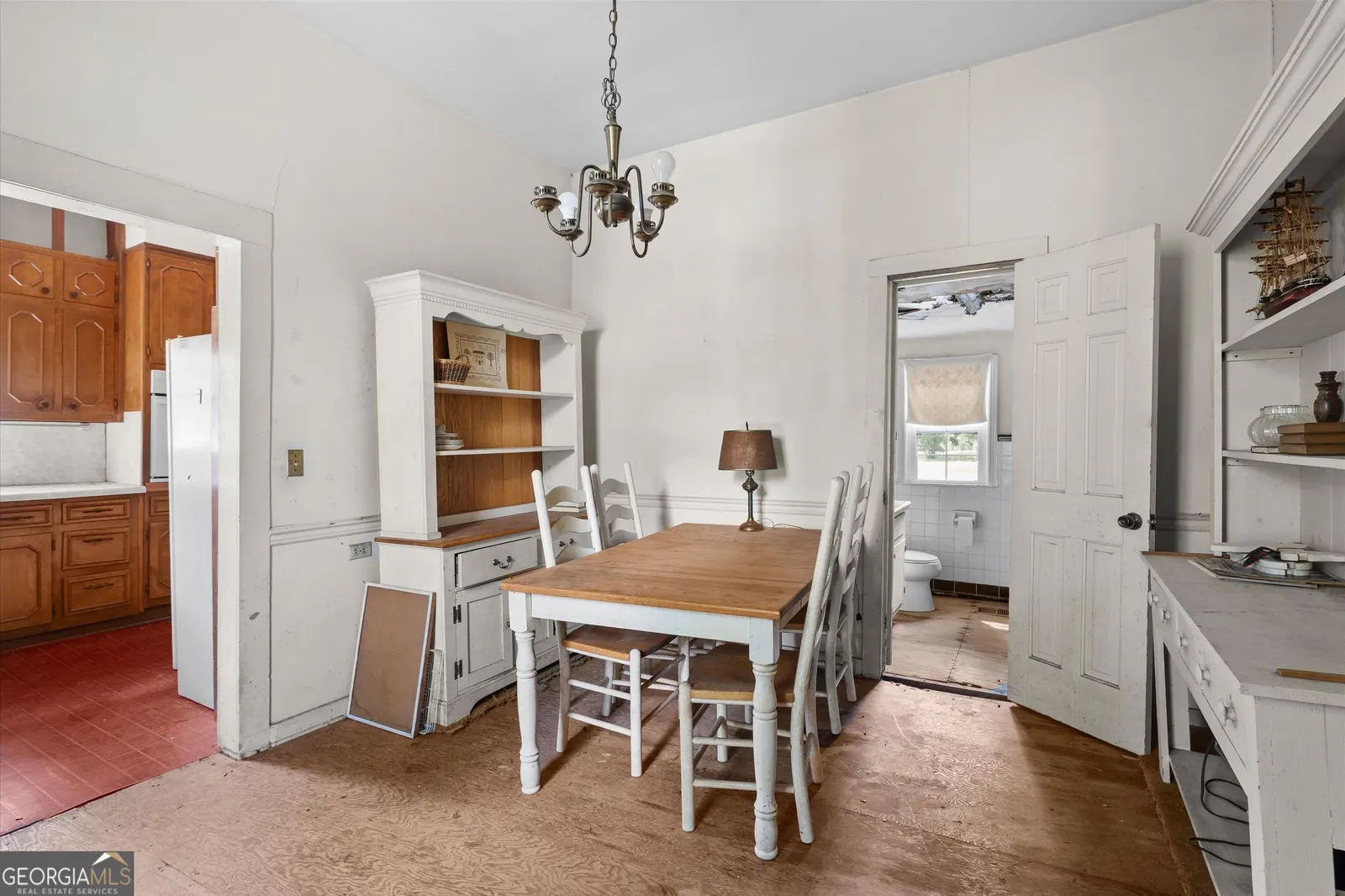 Dining room with a chandelier, a wooden table with ladder-back chairs and a built-in hutch