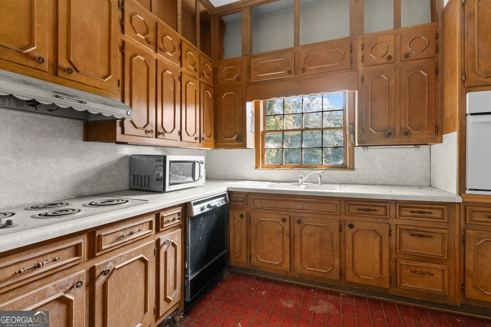 Kitchen with oak cabinets, a white cooktop and a window above the sink