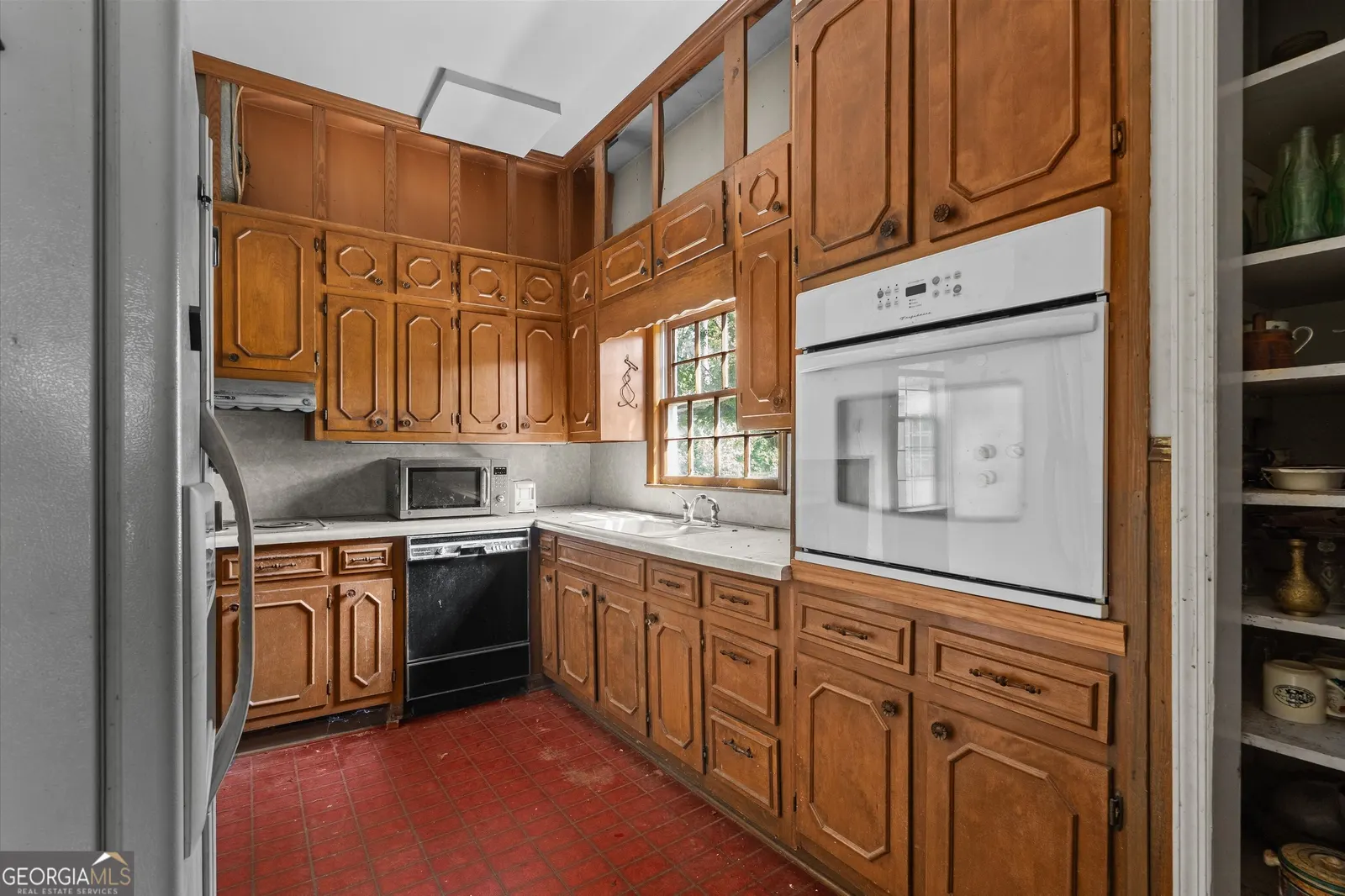 Kitchen from the other side, with a white wall oven and a stainless steel refrigerator