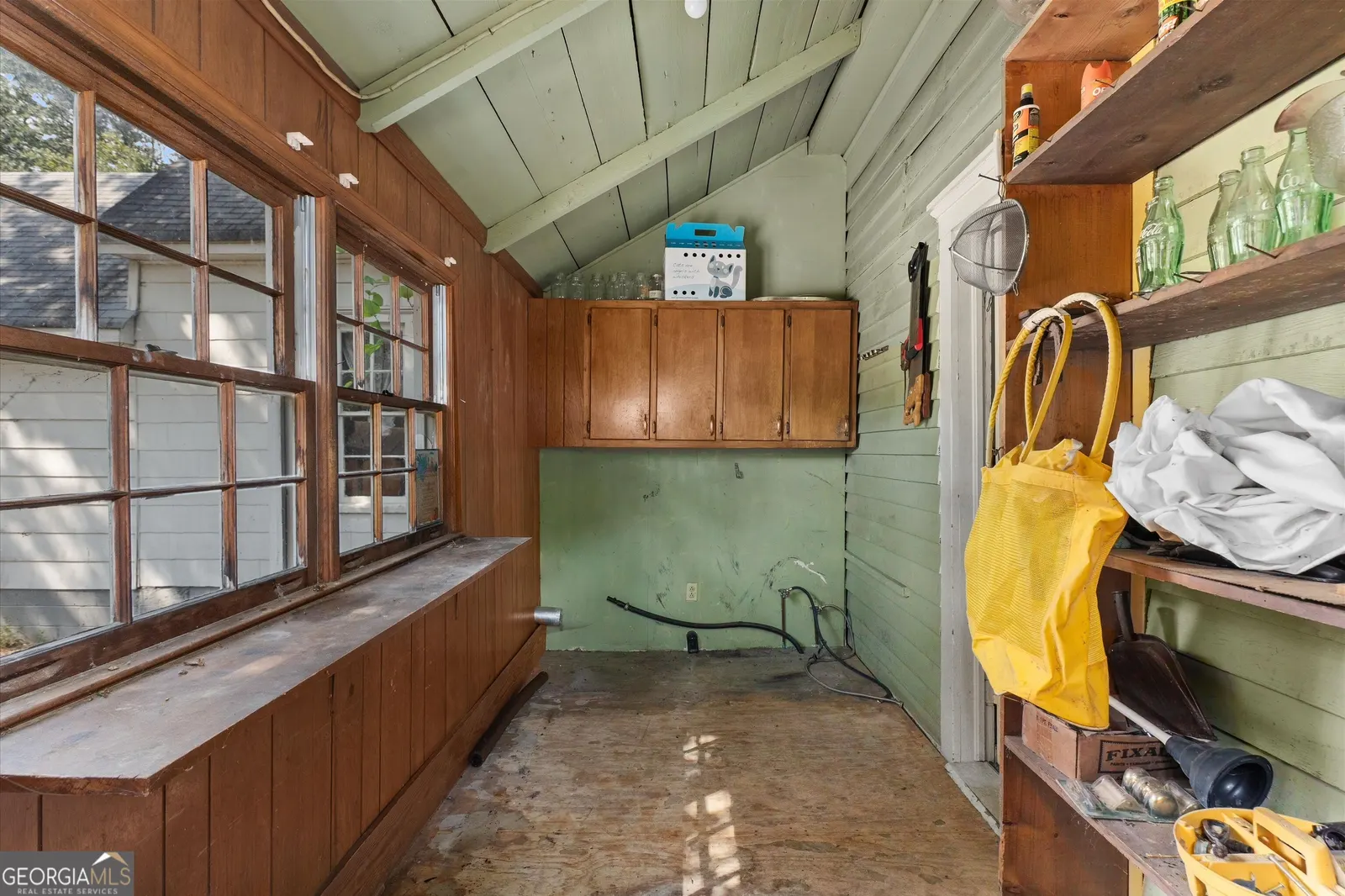 Enclosed porch with green painted board walls, a vaulted ceiling and a bank of windows