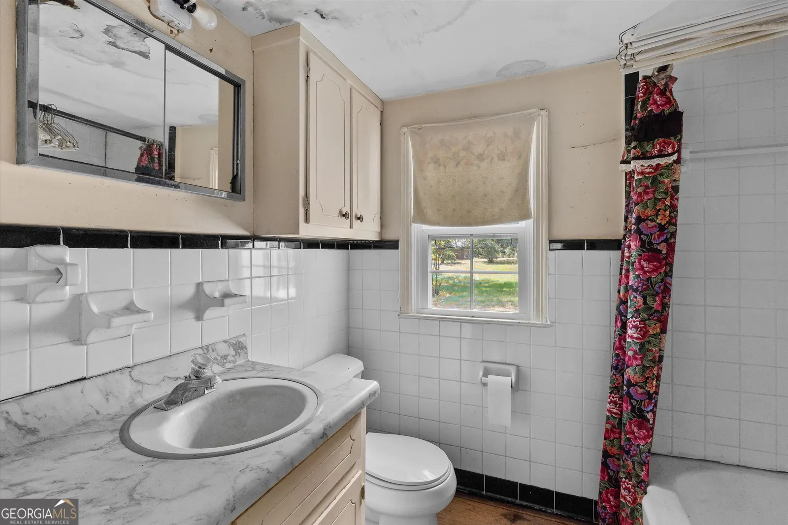 Second bathroom with white tile walls, black trim and a marble-look vanity top