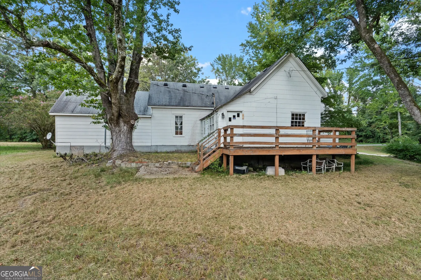 Rear of the house with a wooden deck and a large shade tree