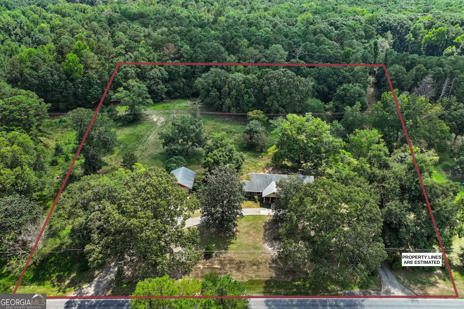 Aerial view with the 4-acre parcel boundary outlined in red around the house and its clearing