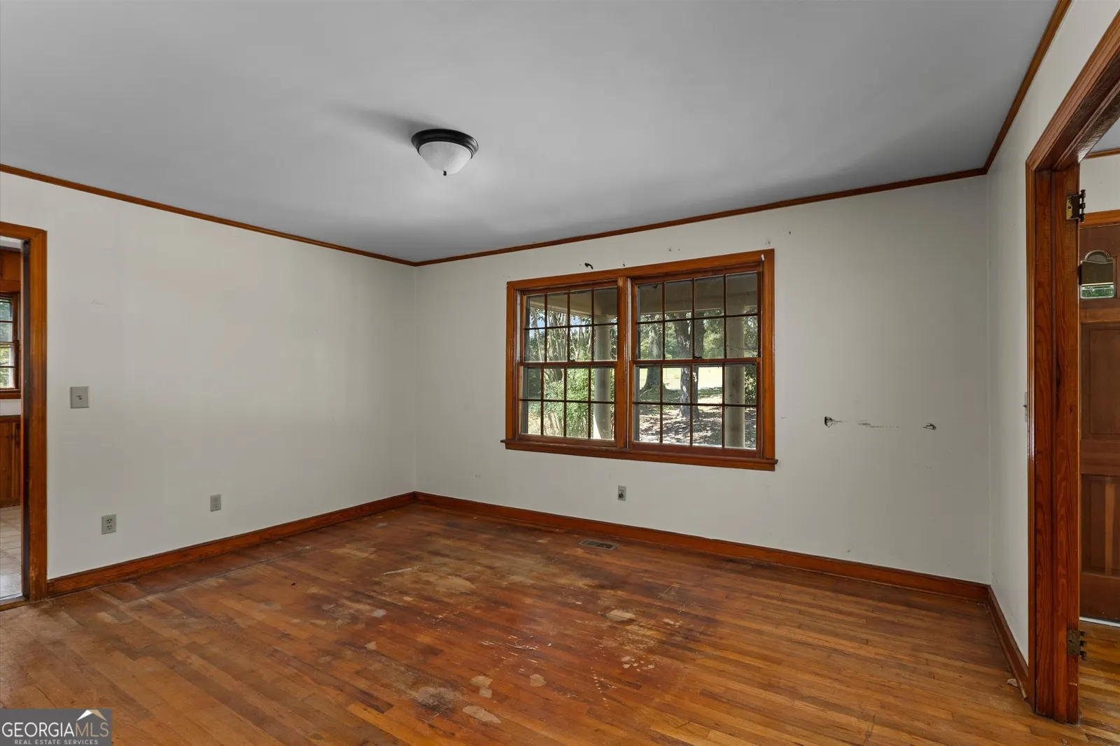 Empty room with a bank of wood-framed windows and hardwood floors