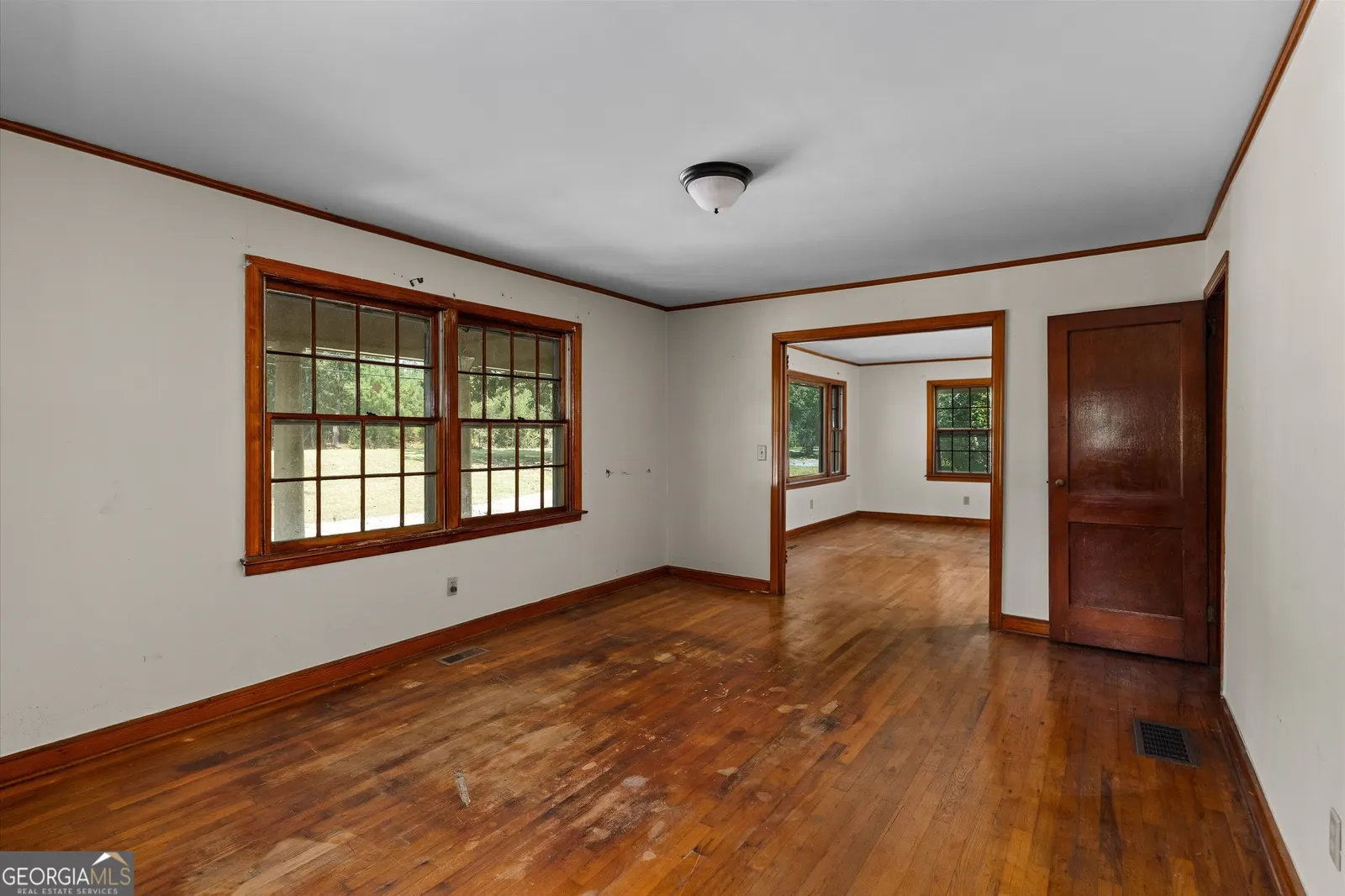 Room with hardwood floors looking through to the next room beyond