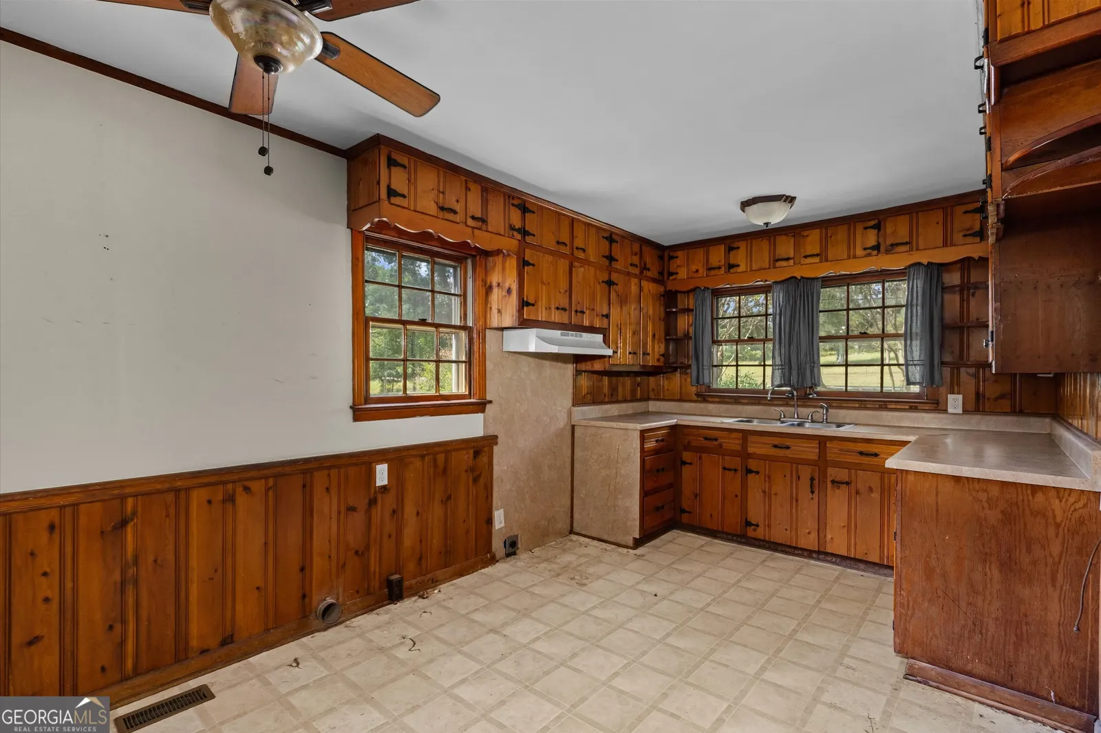 Kitchen with knotty pine cabinets, wood wainscoting and a window above the sink