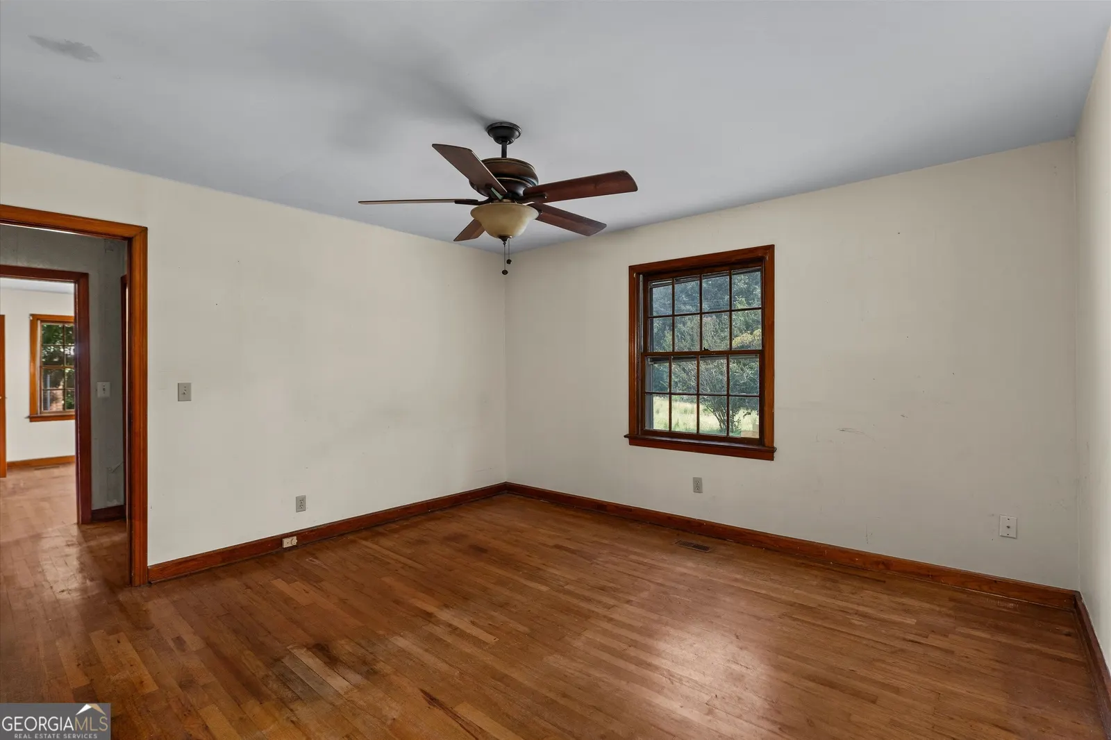 Empty room with white walls, hardwood floors and a ceiling fan