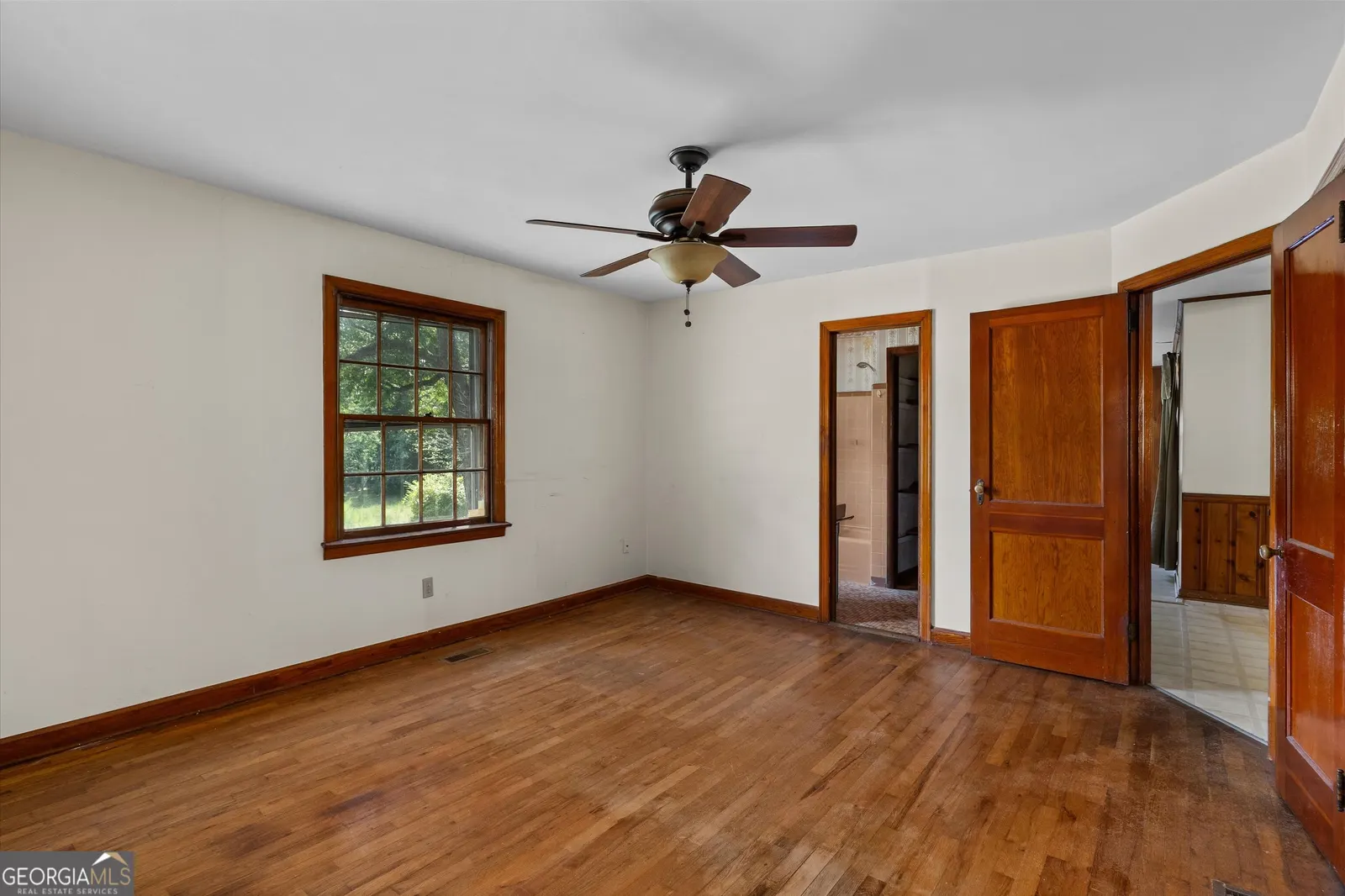 Bedroom with hardwood floors and a mirrored closet door