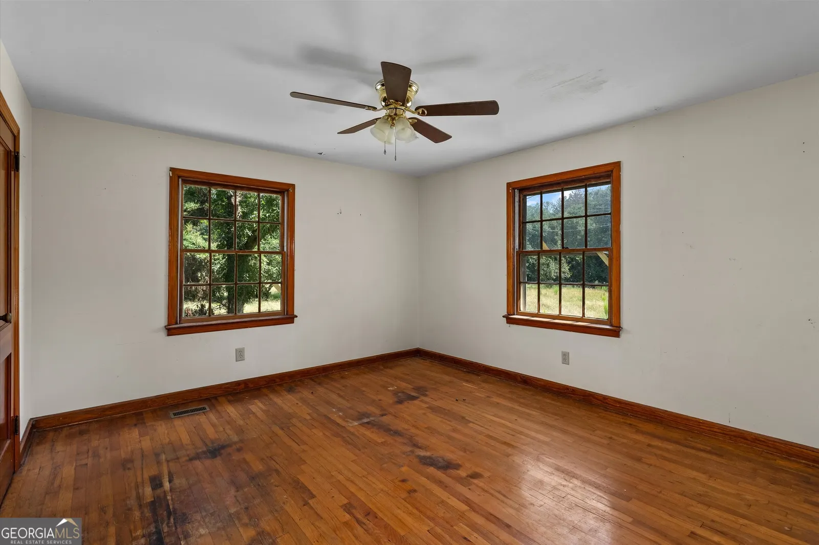 Bedroom with two windows, hardwood floors and a ceiling fan