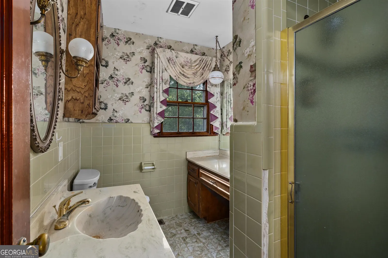 Second bathroom with patterned wallpaper, green tile and a glass shower door