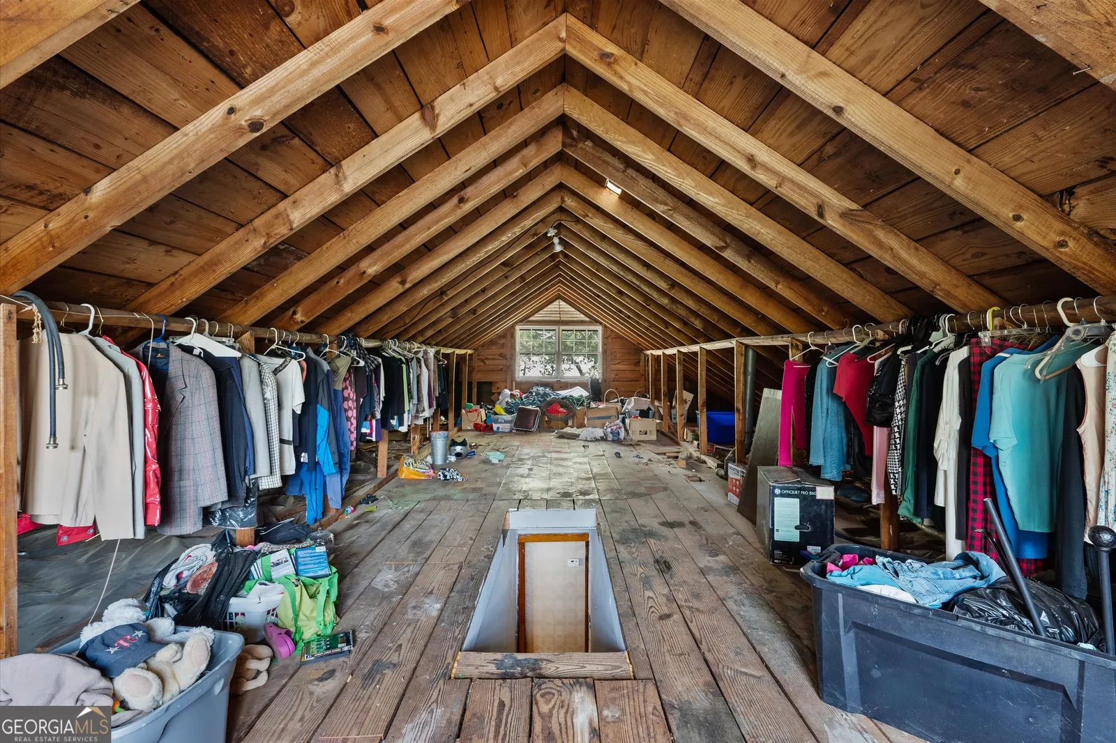 Floored attic under exposed rafters, currently used for hanging storage