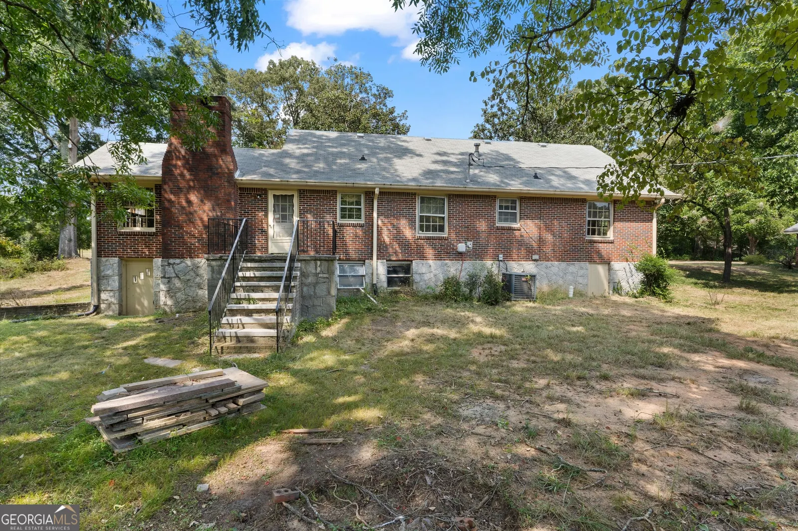 Rear of the brick house, with steps down to the back yard and the chimney stack