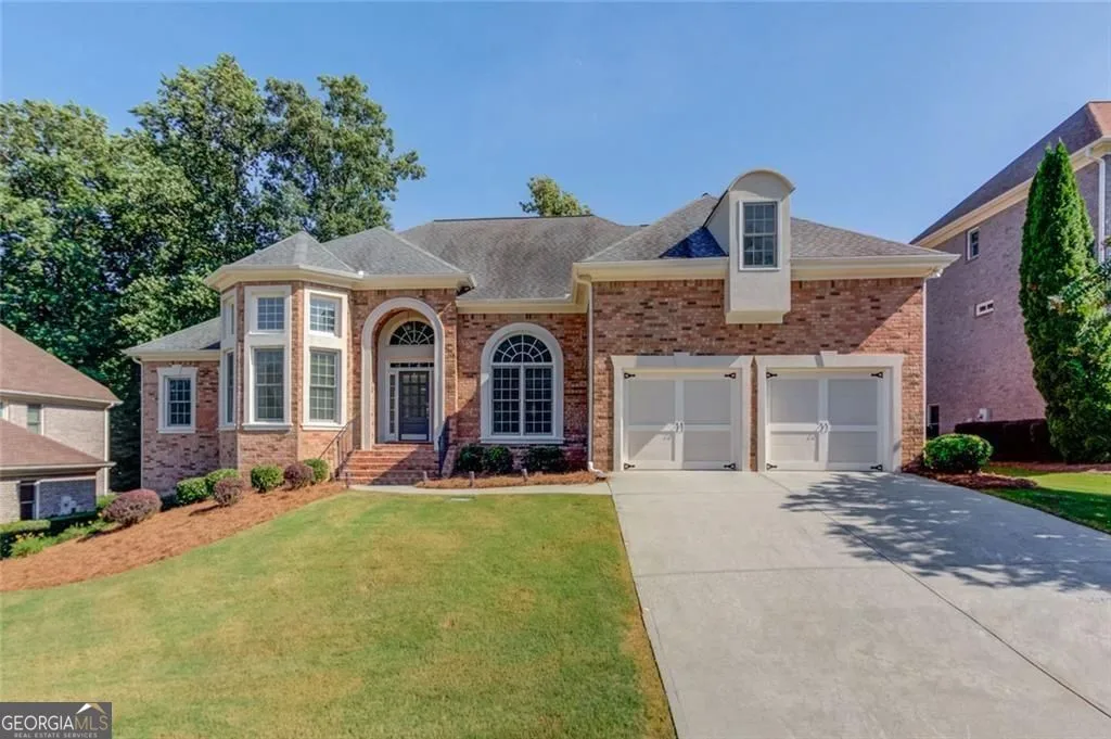 Front of the brick two-story at 2640 Ivy Brook Ln NE, with an arched entry, a bay window and a two-car garage
