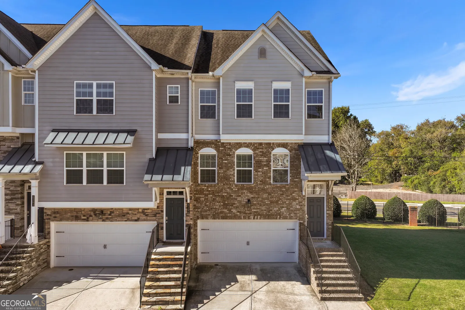 Front of the end-unit townhouse at 4266 Buford Valley Way: brick lower floors, grey siding above and a double garage door, with a lawn on the corner side