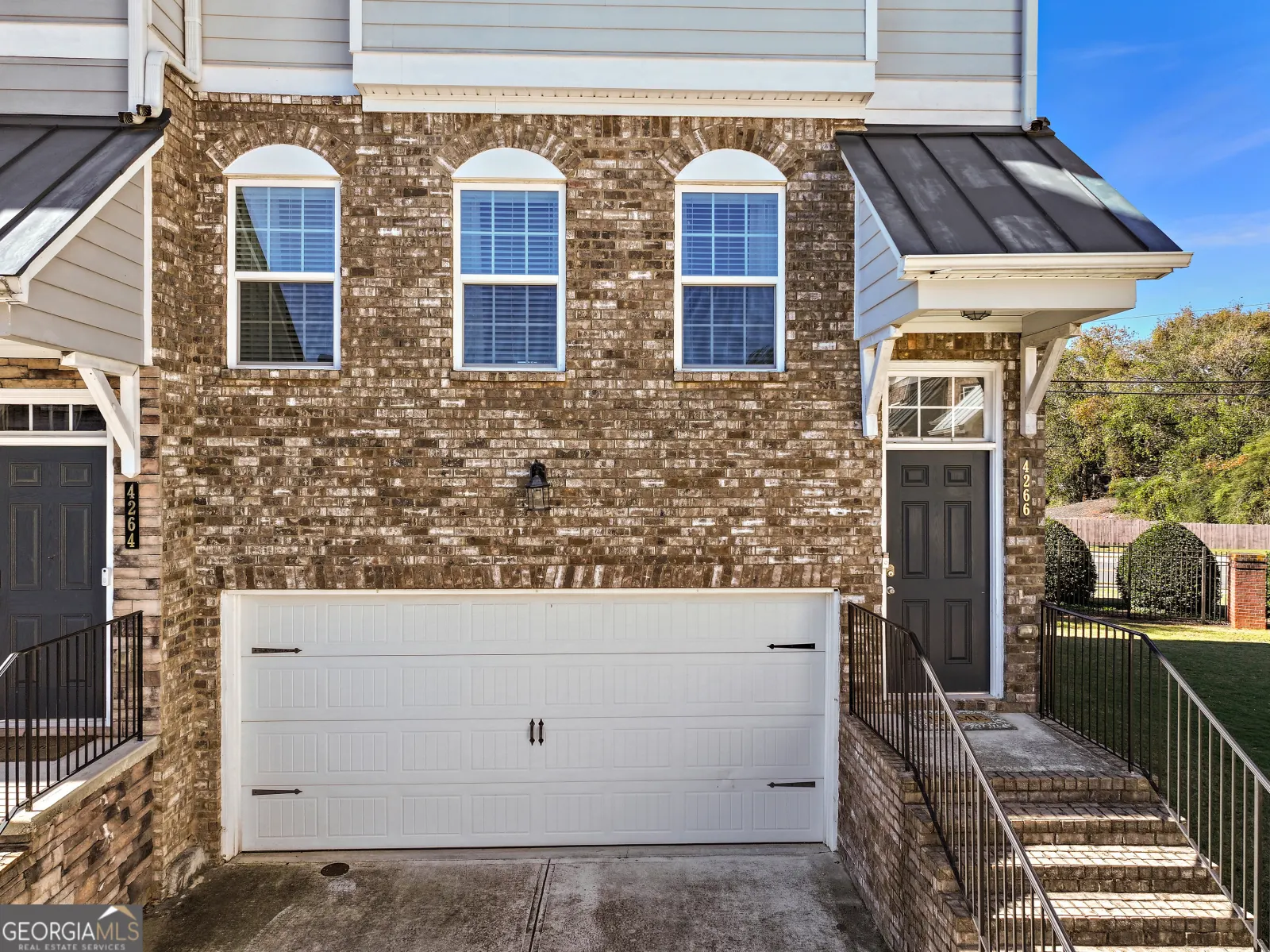 Brick front of the end unit, with three arched windows above the garage and steps up to the front door