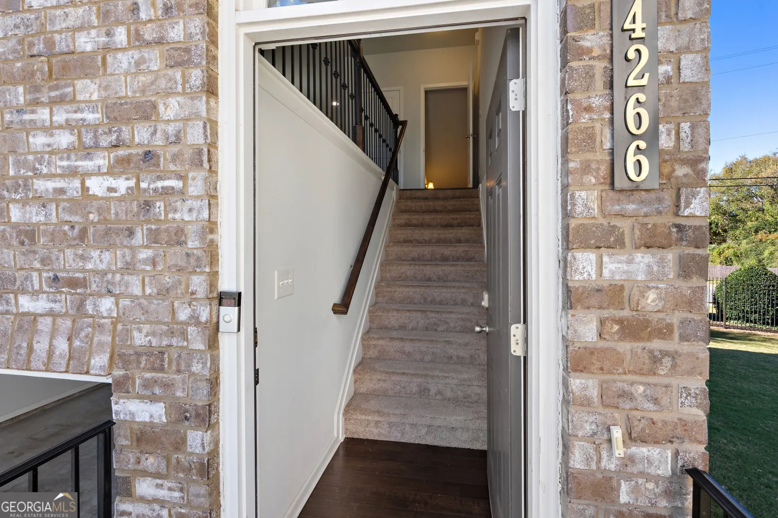 Front door open onto carpeted stairs up to the main level, with the house number 4266 beside it