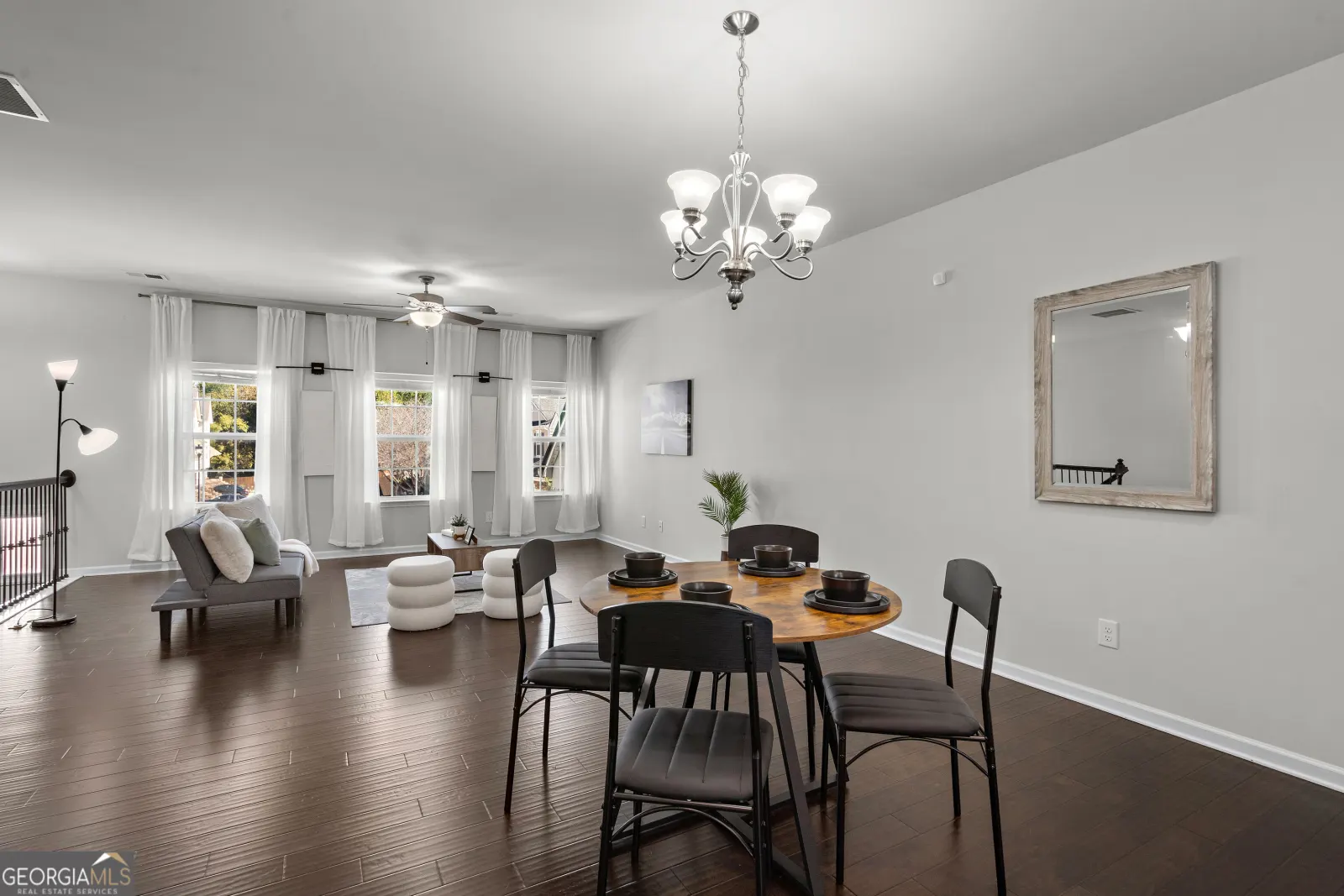 Dining area under a chandelier, open to the living room and its front windows