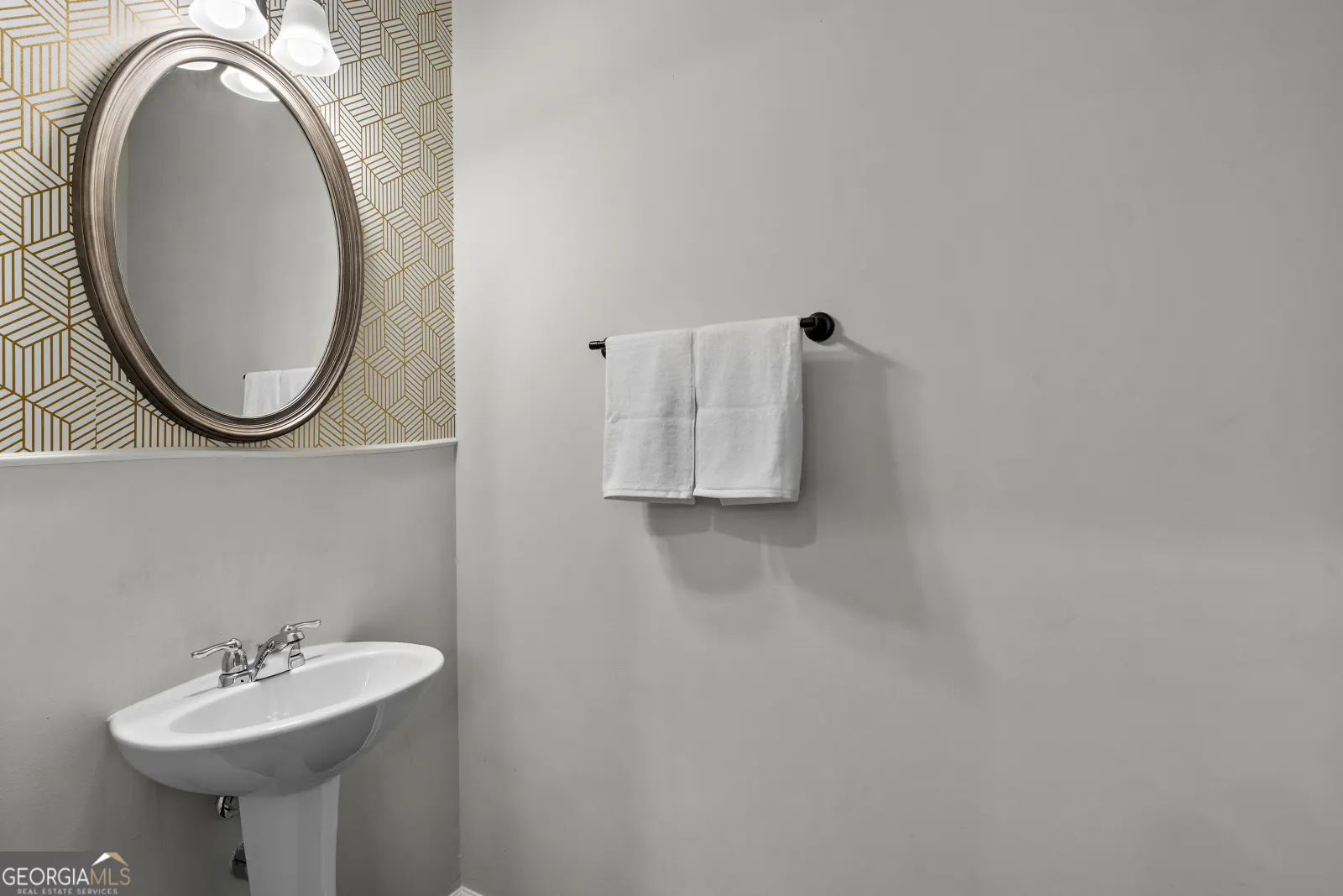 Half bath with a pedestal sink and a patterned wallpaper wall