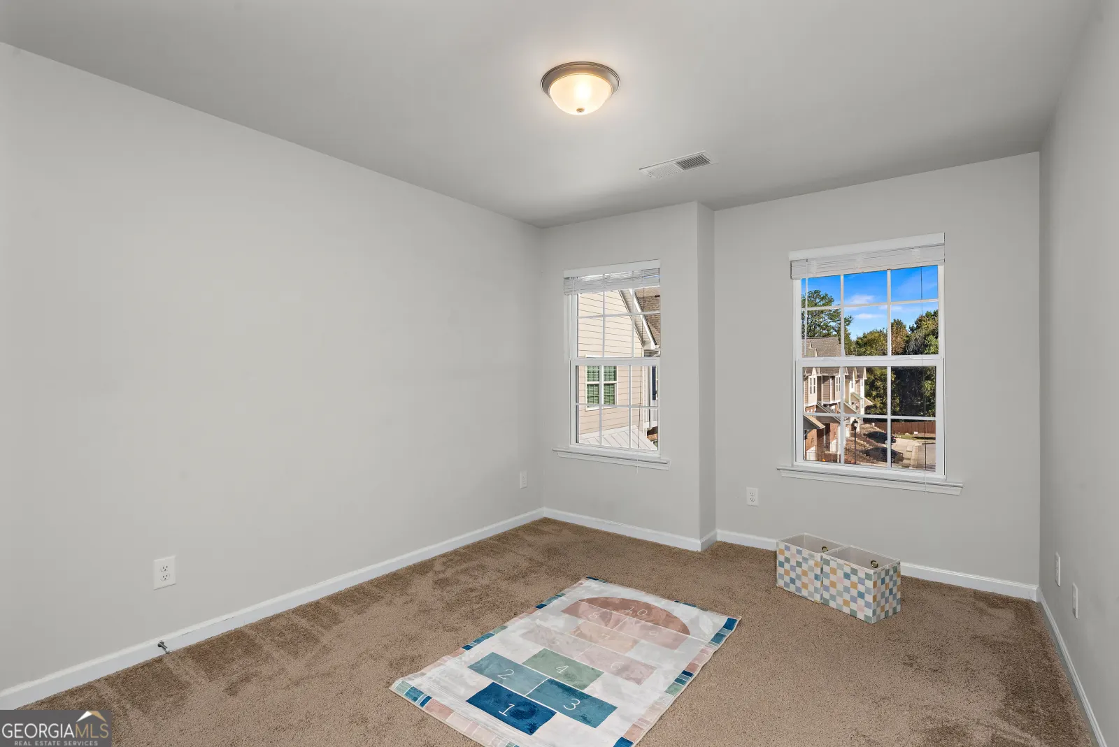 Upstairs bedroom with two windows and carpet