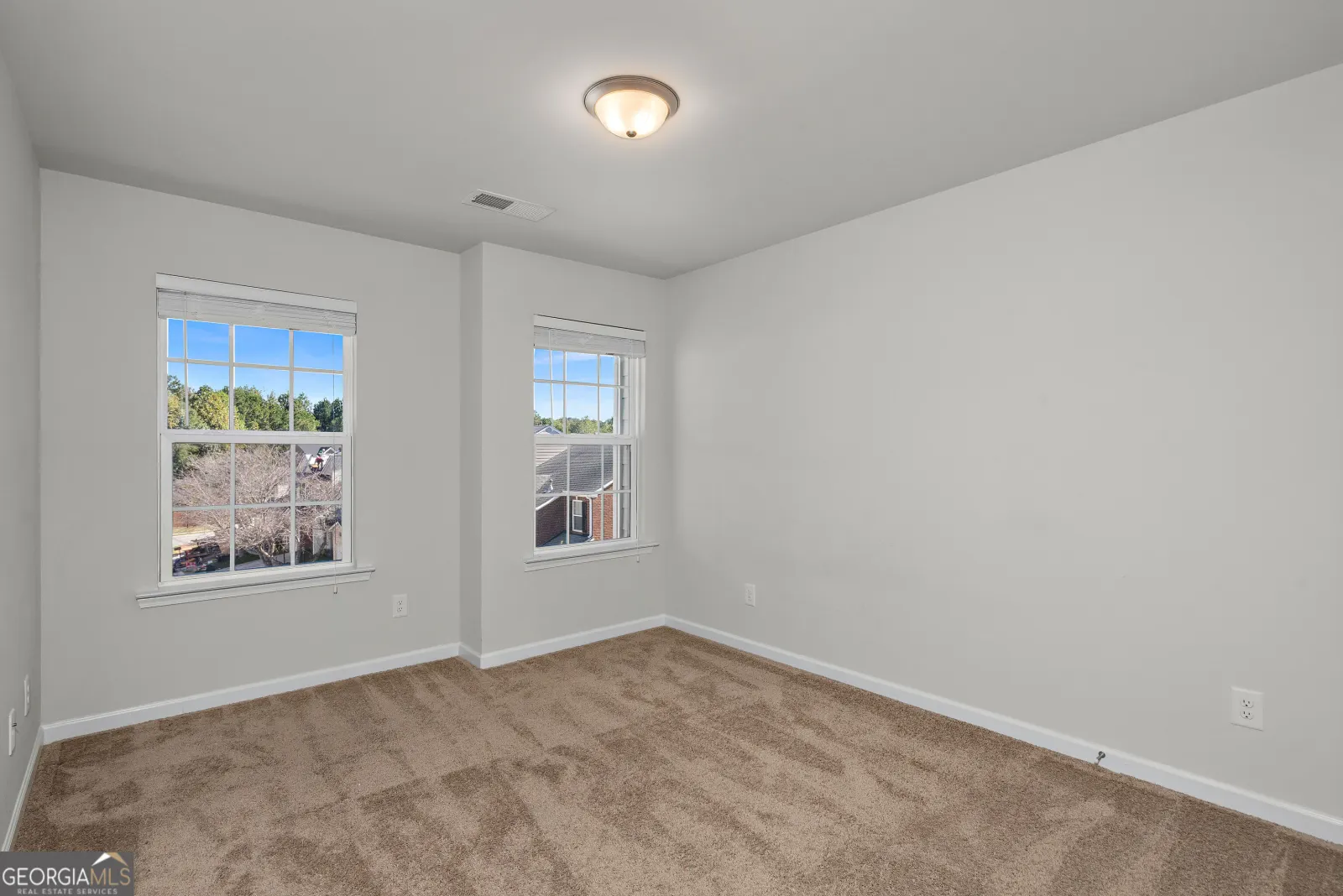Upstairs bedroom with two windows looking out over trees