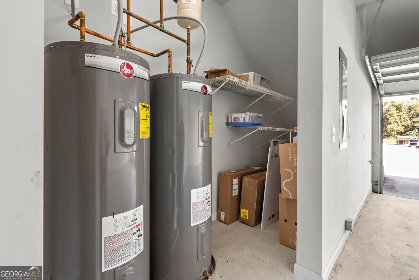 Two water heaters and storage shelving in the garage