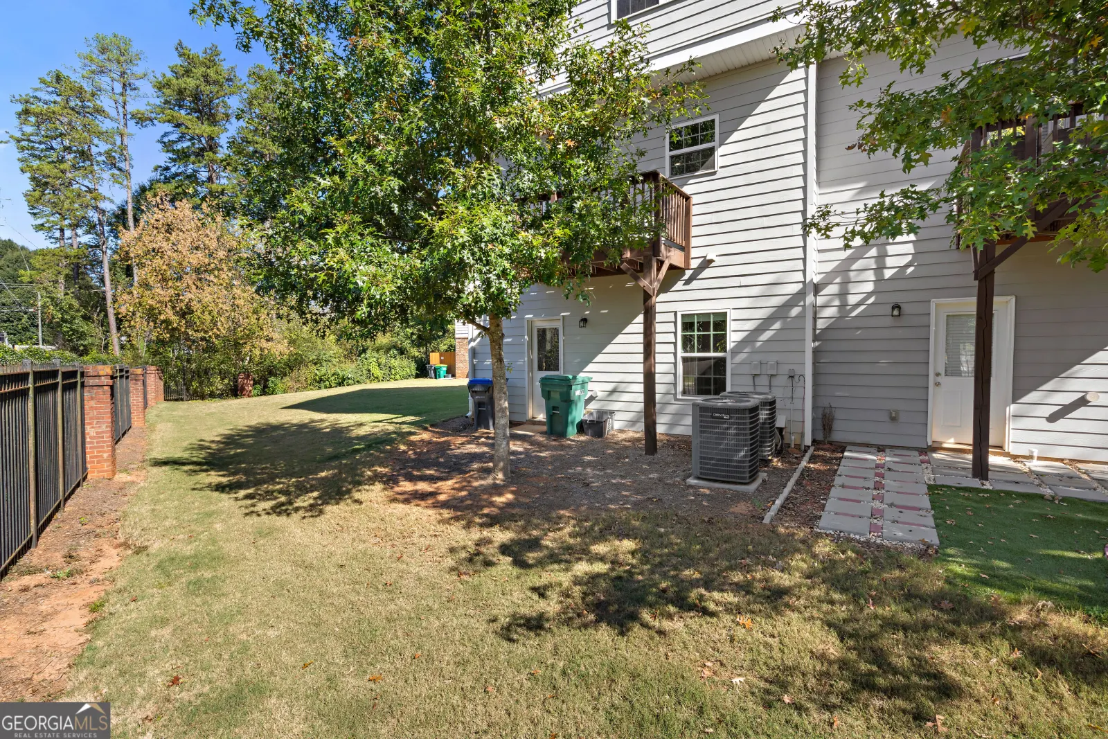 Back of the townhouses, with a strip of lawn and the community fence