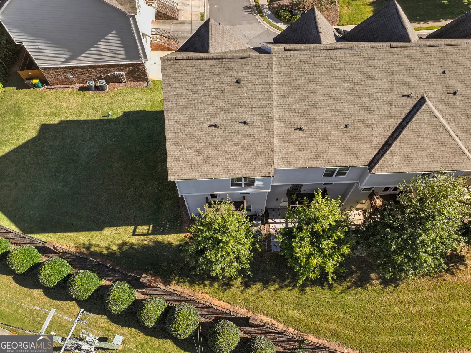 Aerial view of the roof and the side lawn, with a hedge along the street